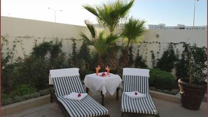 Two striped lounge chairs with white towels, a small round table with a white tablecloth, and a potted plant. - Appart Hotel Founty Beach (Agadir)
