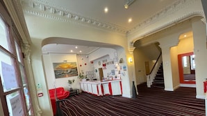 Eine Hotelhalle mit einer Rezeption, einer Treppe und einem roten Sofa.