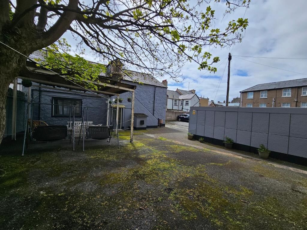 Zona residencial con una casa, un garaje y un patio cercado.