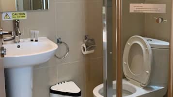 A bathroom with a sink, toilet, and glass shower enclosure.
