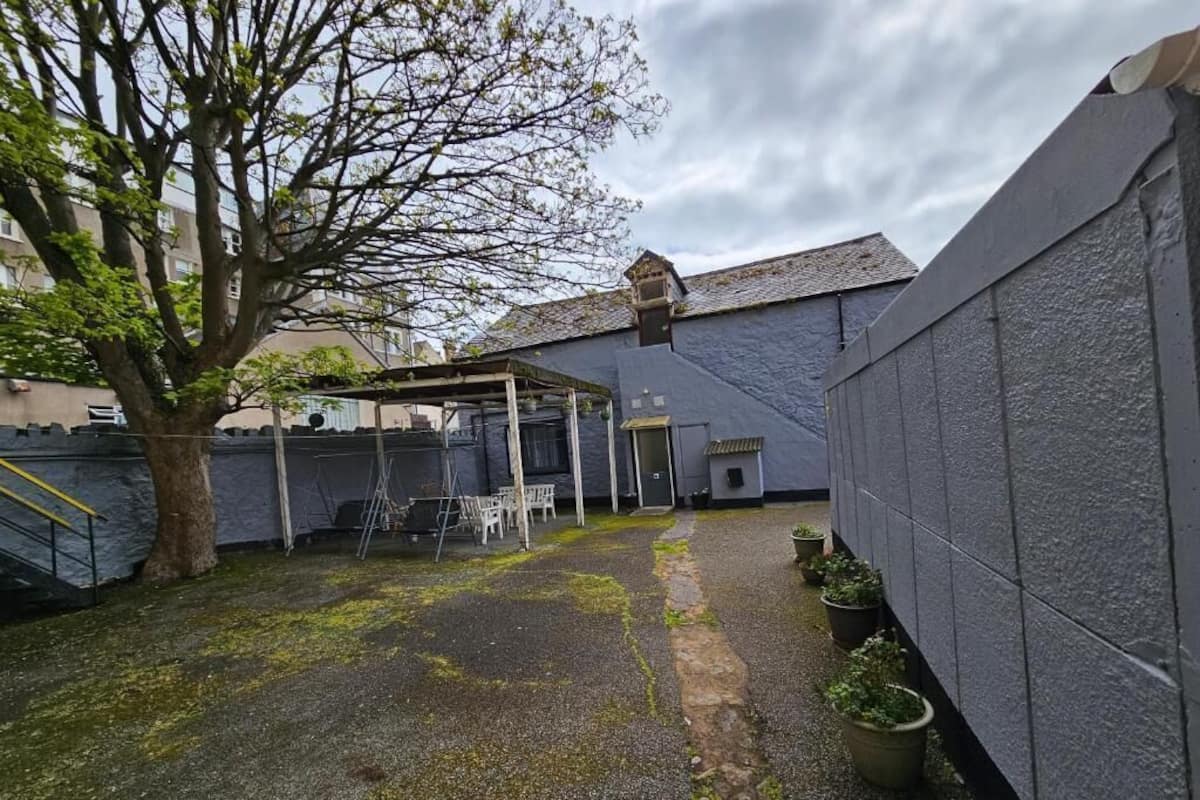 A courtyard with a covered seating area, a tree, and a stone pathway.