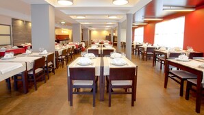 Un restaurant spacieux doté de nombreuses tables et chaises, disposées en ligne avec un passage central.