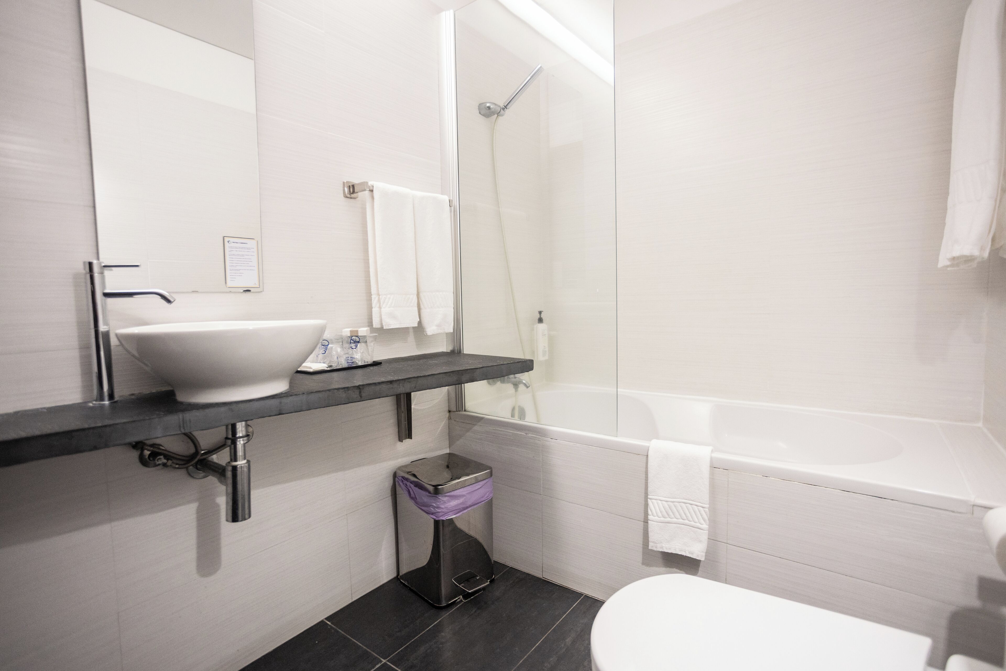 A modern bathroom with a white sink, a mirror, a shower, and a toilet.