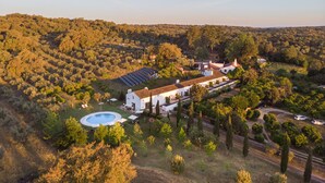 A large estate with a swimming pool, solar panels, and a white building surrounded by trees and hills. - Imani Country House (Évora)