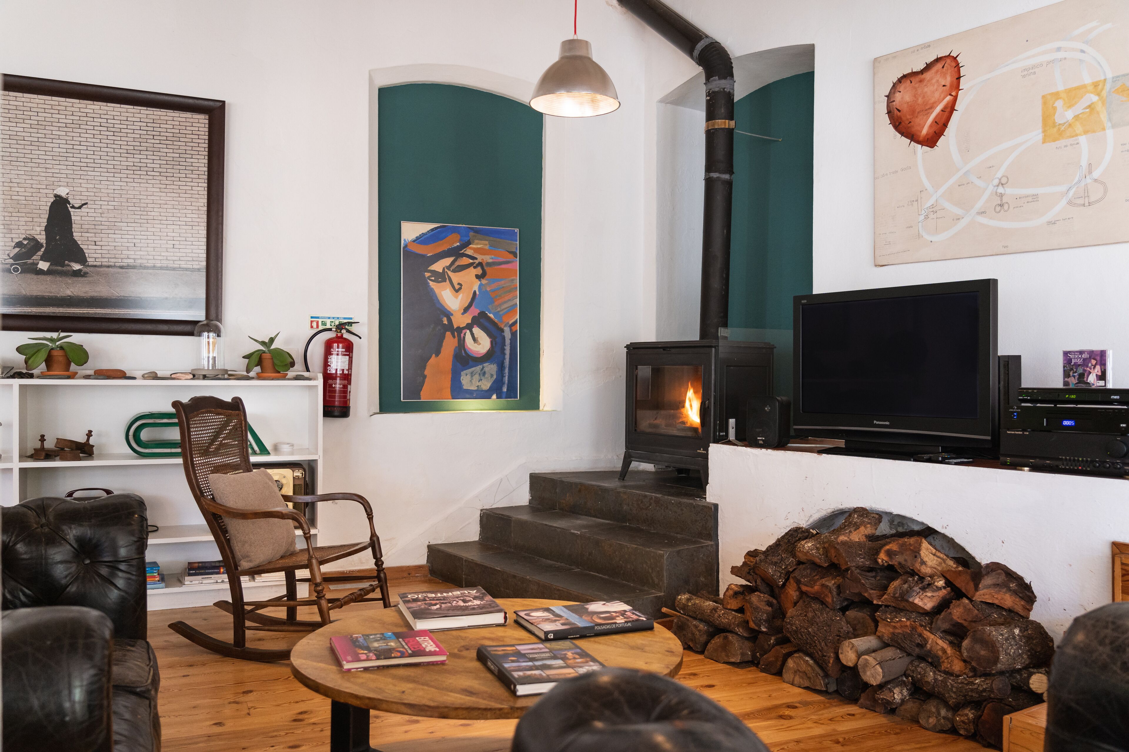 A cozy living room with a fireplace, books, and artwork on the walls.