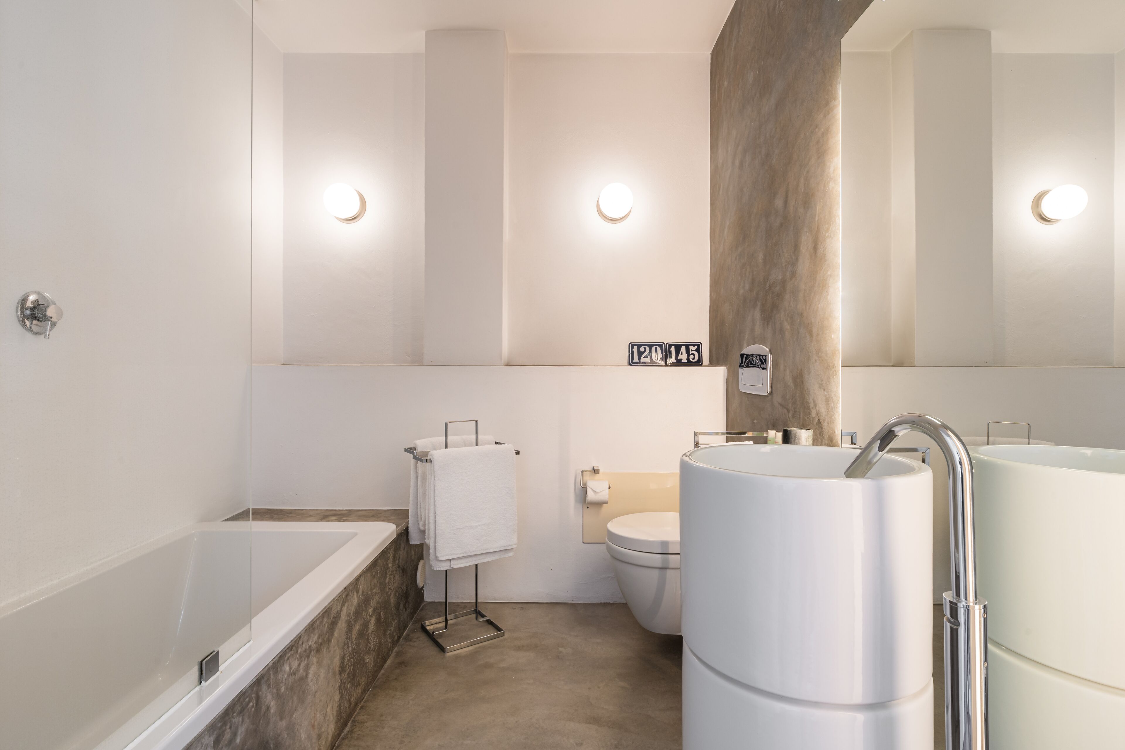 Un bagno moderno con una vasca, un water e due lavabi.