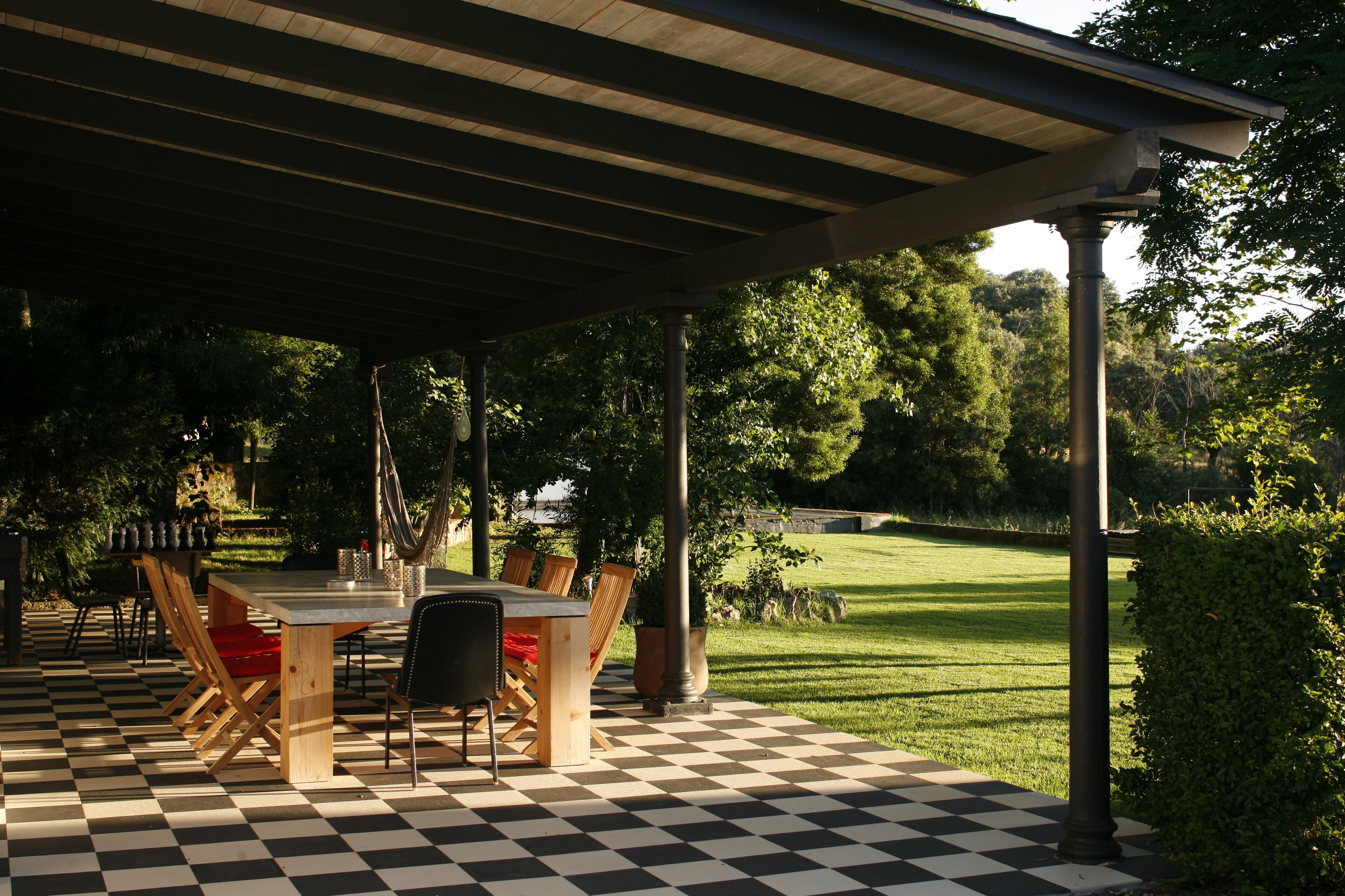 Un patio al aire libre con suelo a cuadros, una mesa de madera y sillas.