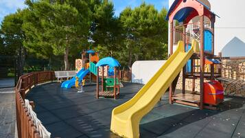 Un parque infantil con un tobogán amarillo, uno azul y una estructura para escalar.