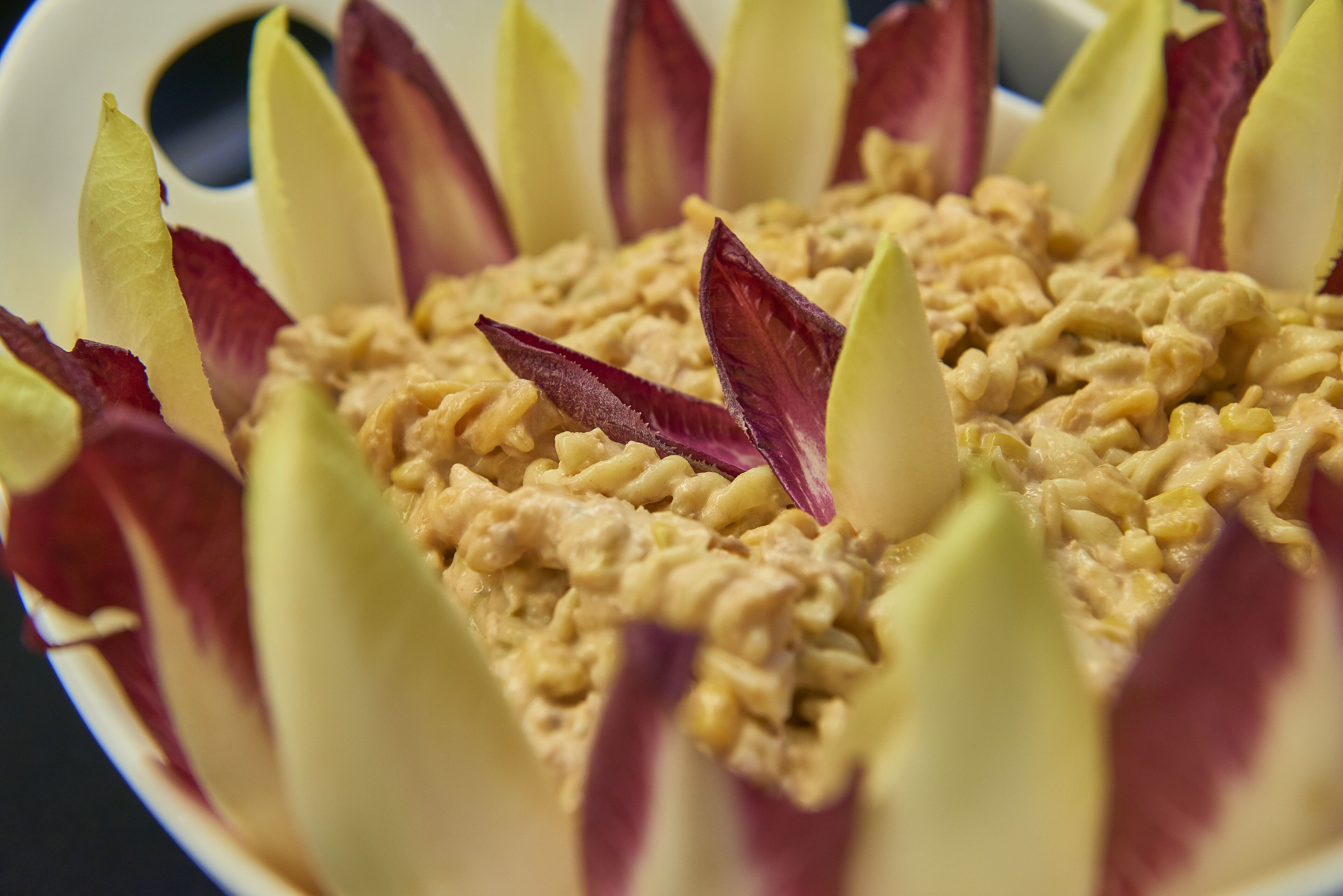 A bowl of pasta with a creamy sauce and garnished with red and yellow leaves.