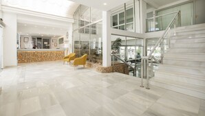 Un vestíbulo amplio con una pared de piedra, un mostrador de recepción y una escalera.