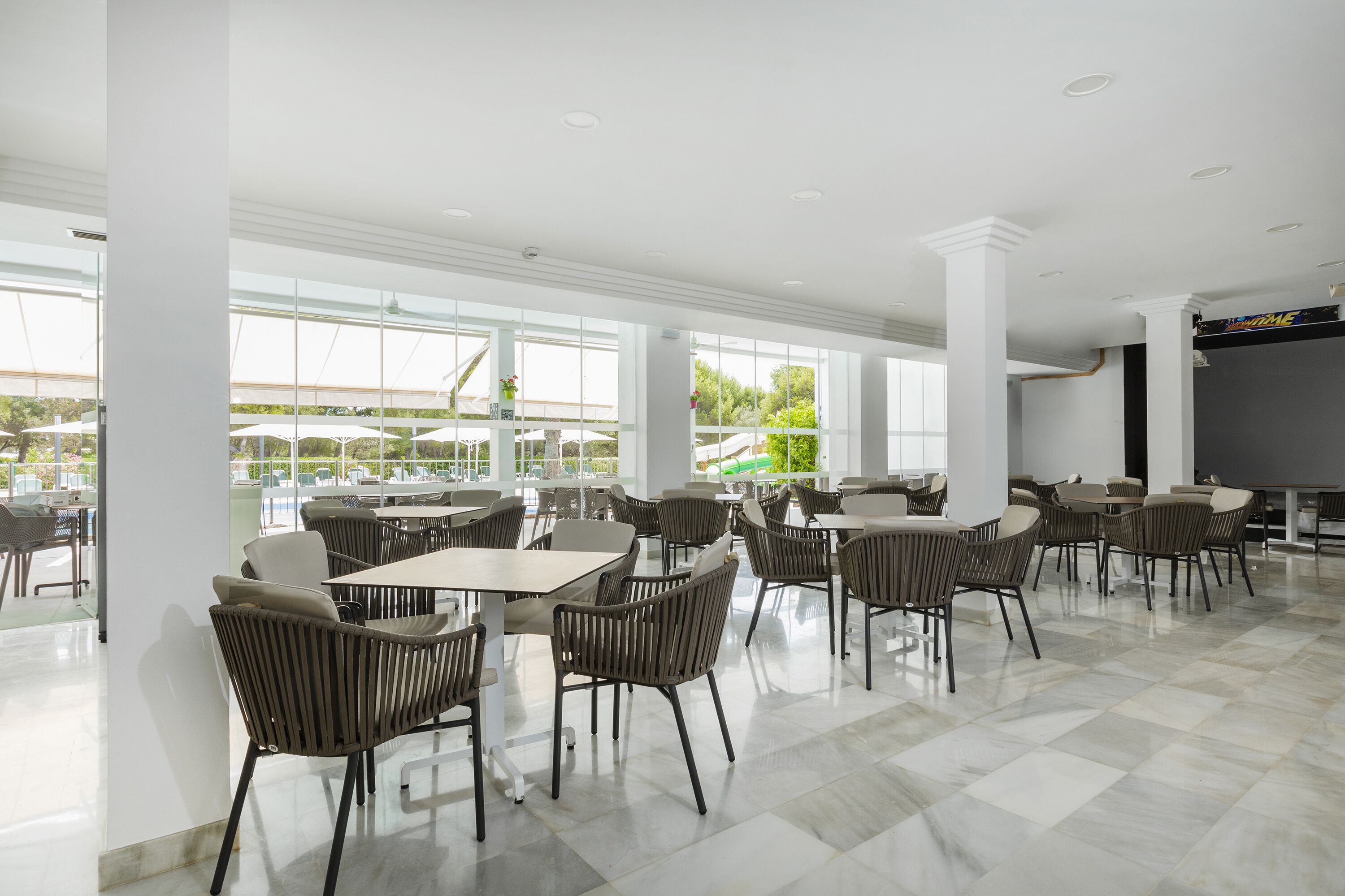 Un comedor interior amplio con techos altos, ventanas grandes y mobiliario moderno.