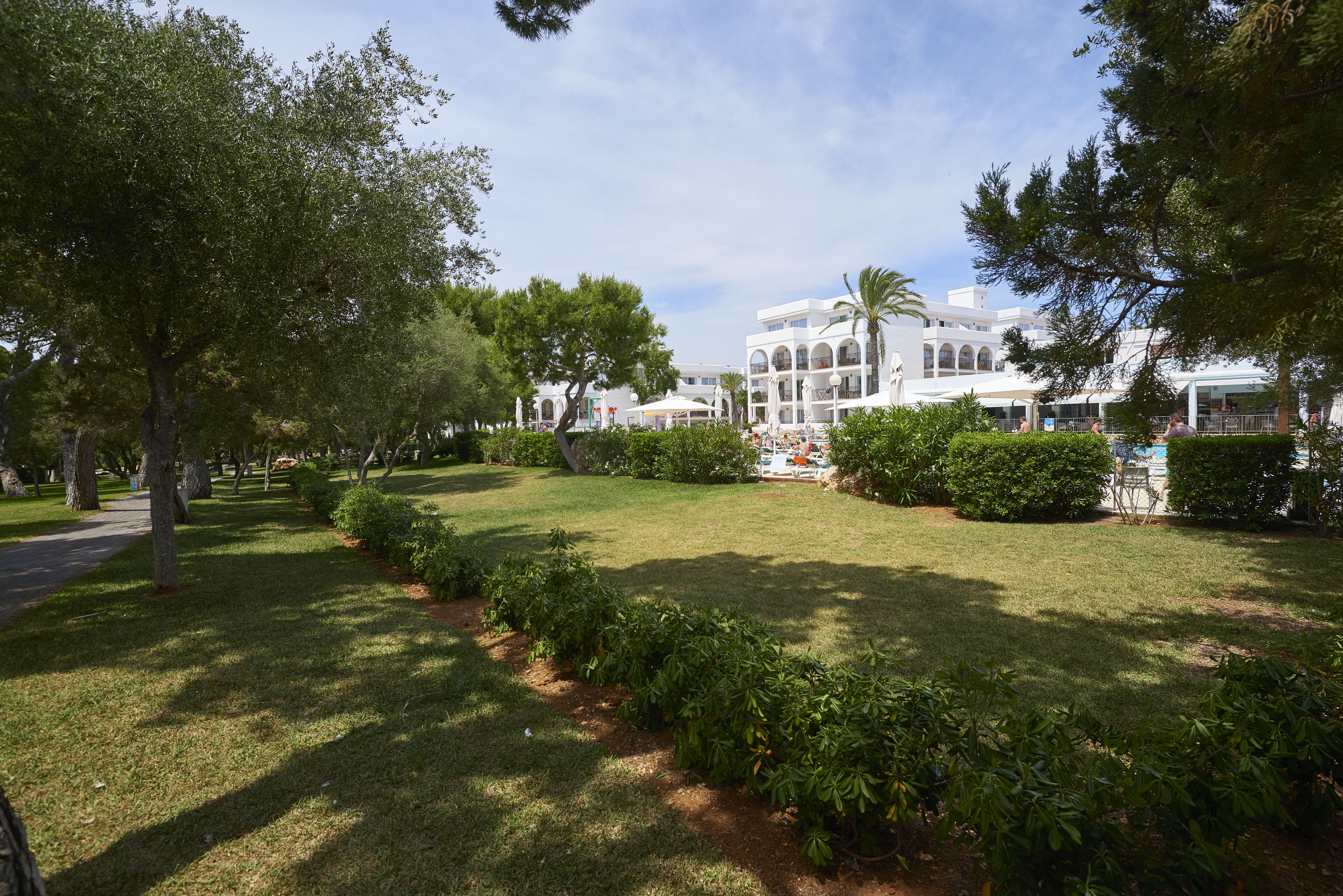 A well-maintained garden with a pathway leading to a white building with multiple balconies.