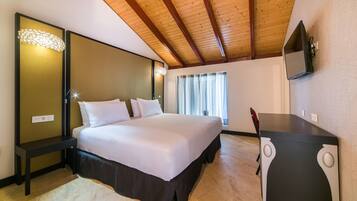 Un dormitorio con cama, escritorio, espejo y ventana con cortinas.