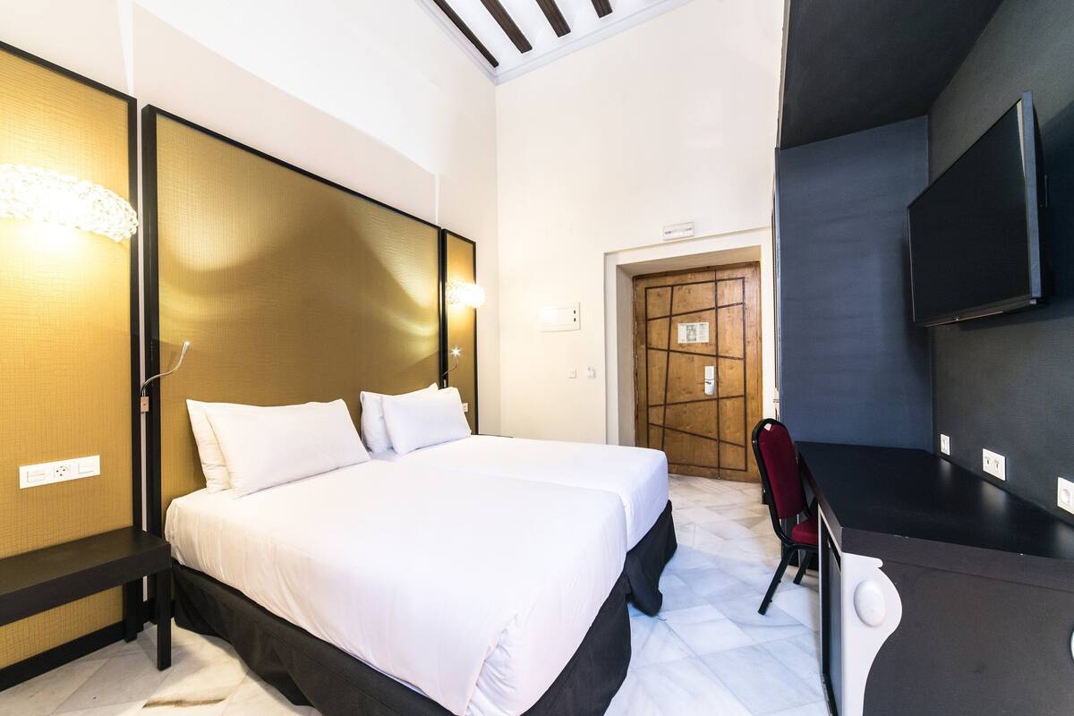 Una habitación de hotel con una cama grande, un escritorio, una silla y un televisor.