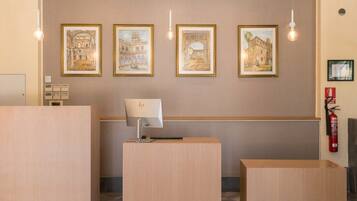 Un espace d’accueil avec des comptoirs de réception en bois, une lampe de bureau, des œuvres d’art encadrées accrochées au mur et un extincteur.
