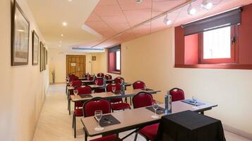 A conference room with tables and chairs, a wooden floor, and a red-framed window.