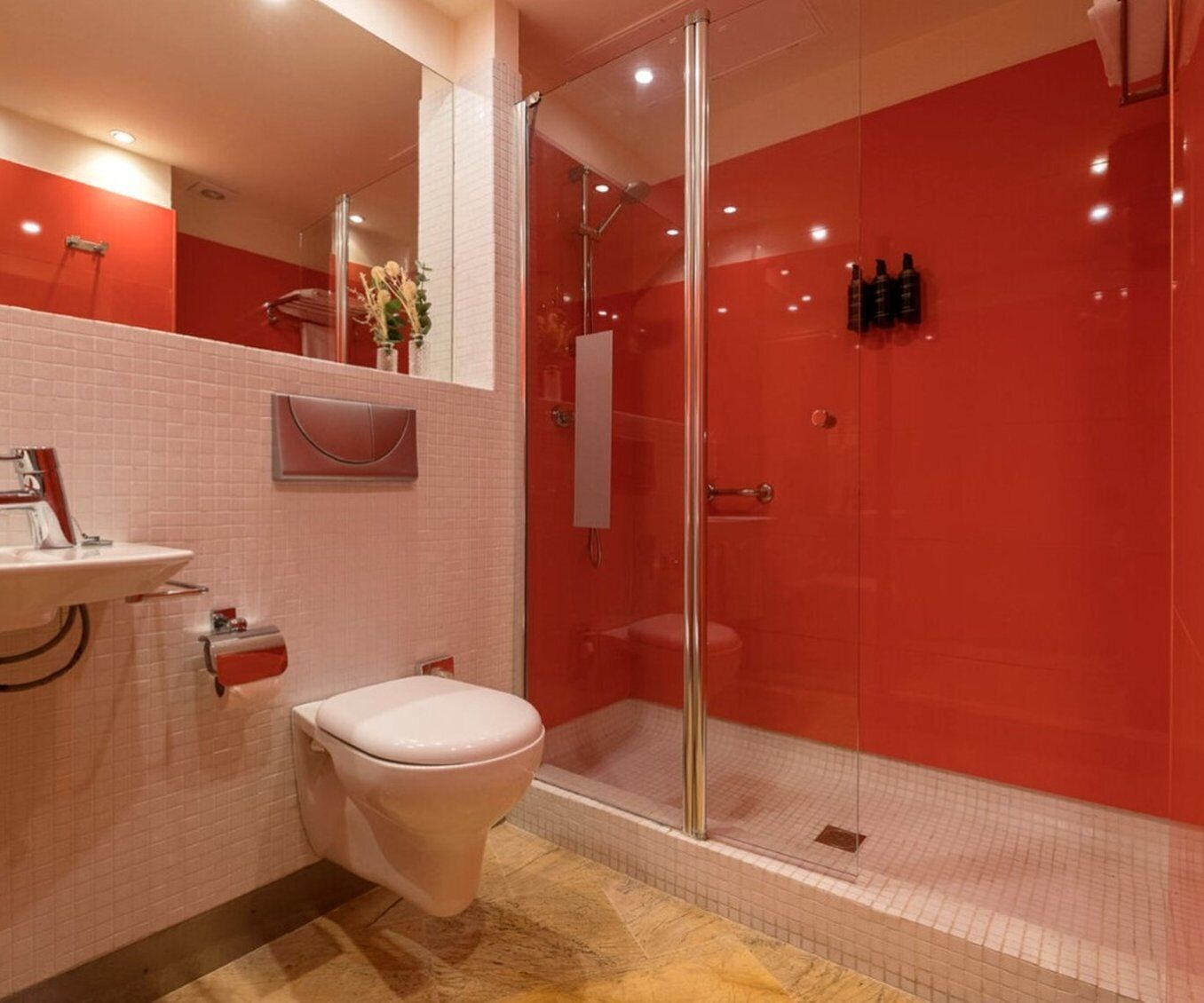 A modern bathroom with a glass-enclosed shower, a white toilet, and a sink with a mirror above it.