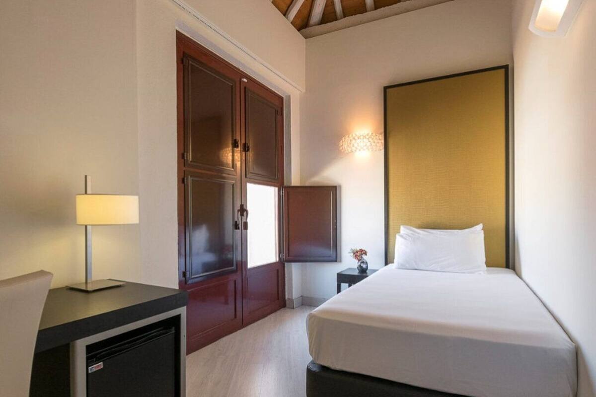 Una habitación de hotel con cama, escritorio, televisor y armario.
