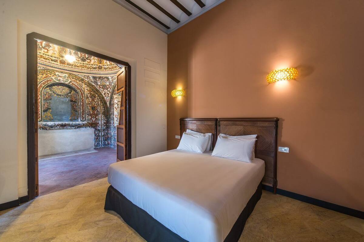 Un dormitorio con una cama grande, cabecera de madera y dos apliques.
