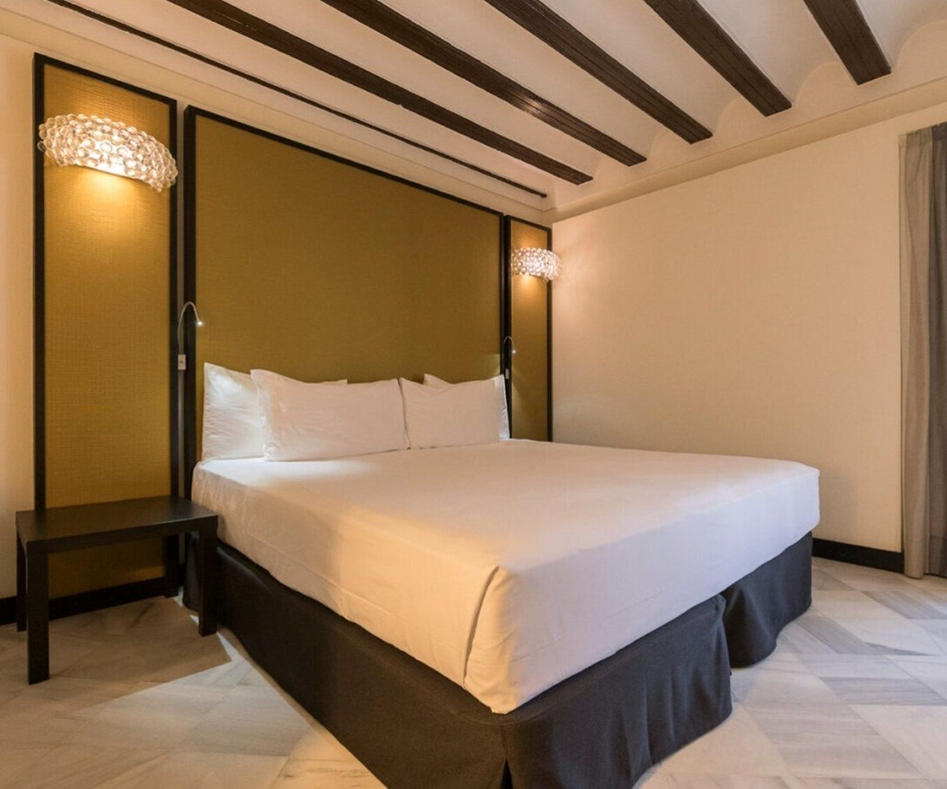 Ein Hotelzimmer mit einem großen Bett, einem Nachttisch und zwei Wandlampen.