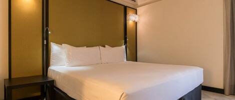A hotel room with a large bed, a nightstand, and two wall-mounted lamps.
