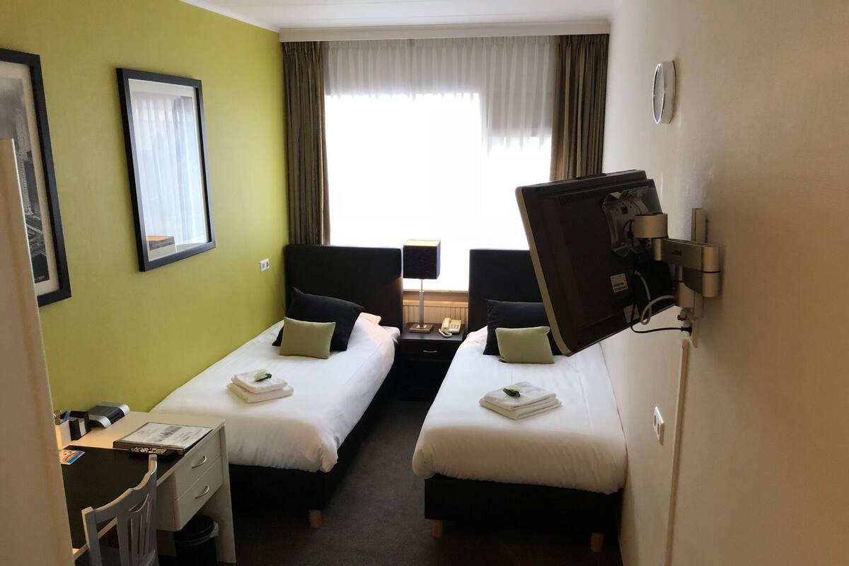 Een hotelkamer met twee bedden, een bureau, een stoel en een televisie.