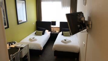 A hotel room with two beds, a desk, a chair, and a TV.