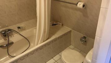 A bathroom with a bathtub, toilet, and shower curtain.