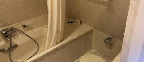 Un baño con bañera, inodoro y cortina de ducha.