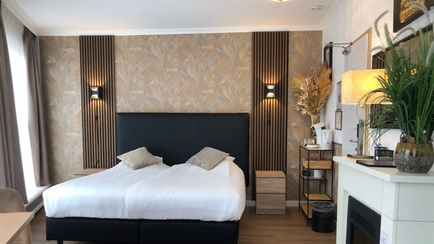A modern hotel room with a large bed, a fireplace, and a desk. - Hotel De Keizerskroon (Hoorn)