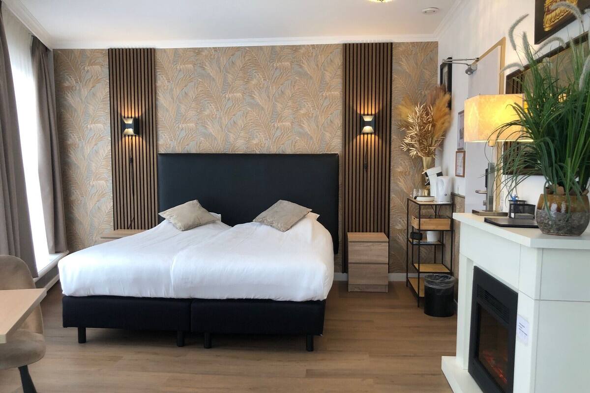 Een moderne hotelkamer met een groot bed, een open haard en een bureau.