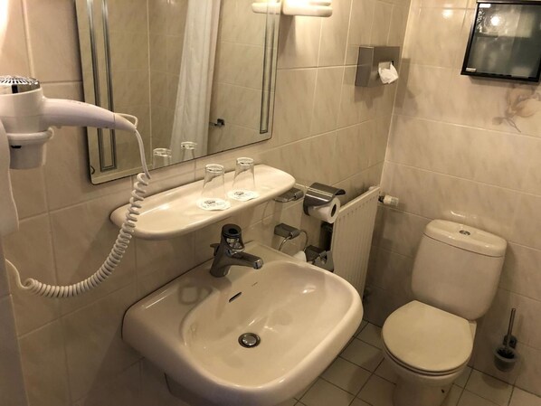 Un baño con lavamanos, espejo, inodoro y secador de pelo.