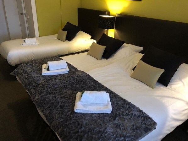 A hotel room with two beds, a dark patterned bed runner, and a bedside lamp. - Hotel De Keizerskroon (Hoorn)