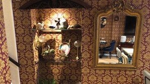 A room with ornate wallpaper, a mirror, and a shelf with decorative items. - Hotel De Keizerskroon (Hoorn)