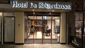 Hotel De Keizerskroon with a glass entrance, a crown decoration, and a visible interior with tables and chairs. - Hotel De Keizerskroon (Hoorn)