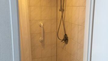 Une petite salle de douche carrelée, équipée d’un pommeau de douche, d’un pommeau de douche à main et d’un drain.