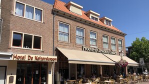 A hotel with a brick facade, multiple windows, and outdoor seating area with wicker chairs. - Hotel De Keizerskroon (Hoorn)