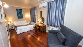 Ein Hotelzimmer mit Bett, Schreibtisch, Sessel, Sofa und Heizkörper.
