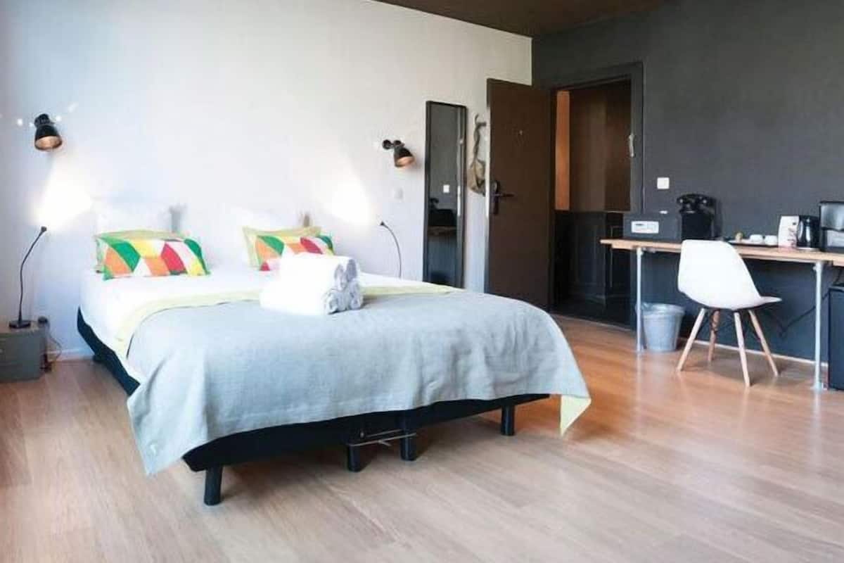 A modern hotel room with a bed, a desk, and a chair.