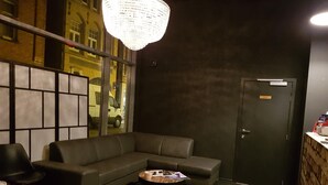 A modern waiting area with a dark-colored sofa, a round coffee table, and a chandelier. - Hotel O Ieper (Ypres)