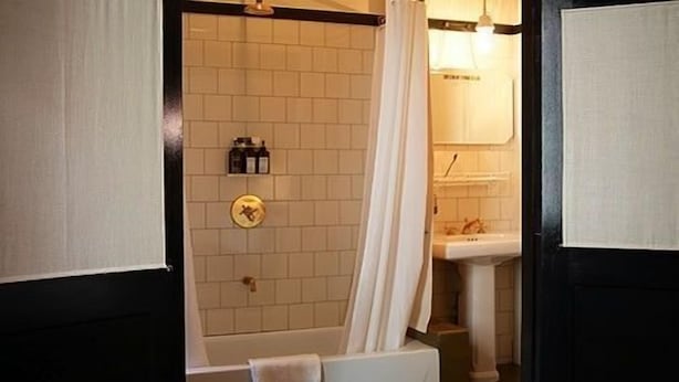 A bathroom with a bathtub, a shower curtain, a sink, and a towel rack. - Hotel O Ieper (Ypres)