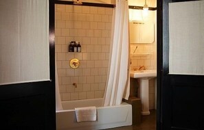 A bathroom with a bathtub, a shower curtain, a sink, and a towel rack. - Hotel O Ieper (Ypres)