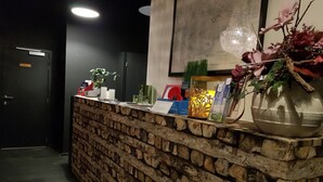 A reception desk with a rustic wooden design, a framed picture on the wall, and various items on the counter including a vase with flowers. - Hotel O Ieper (Ypres)