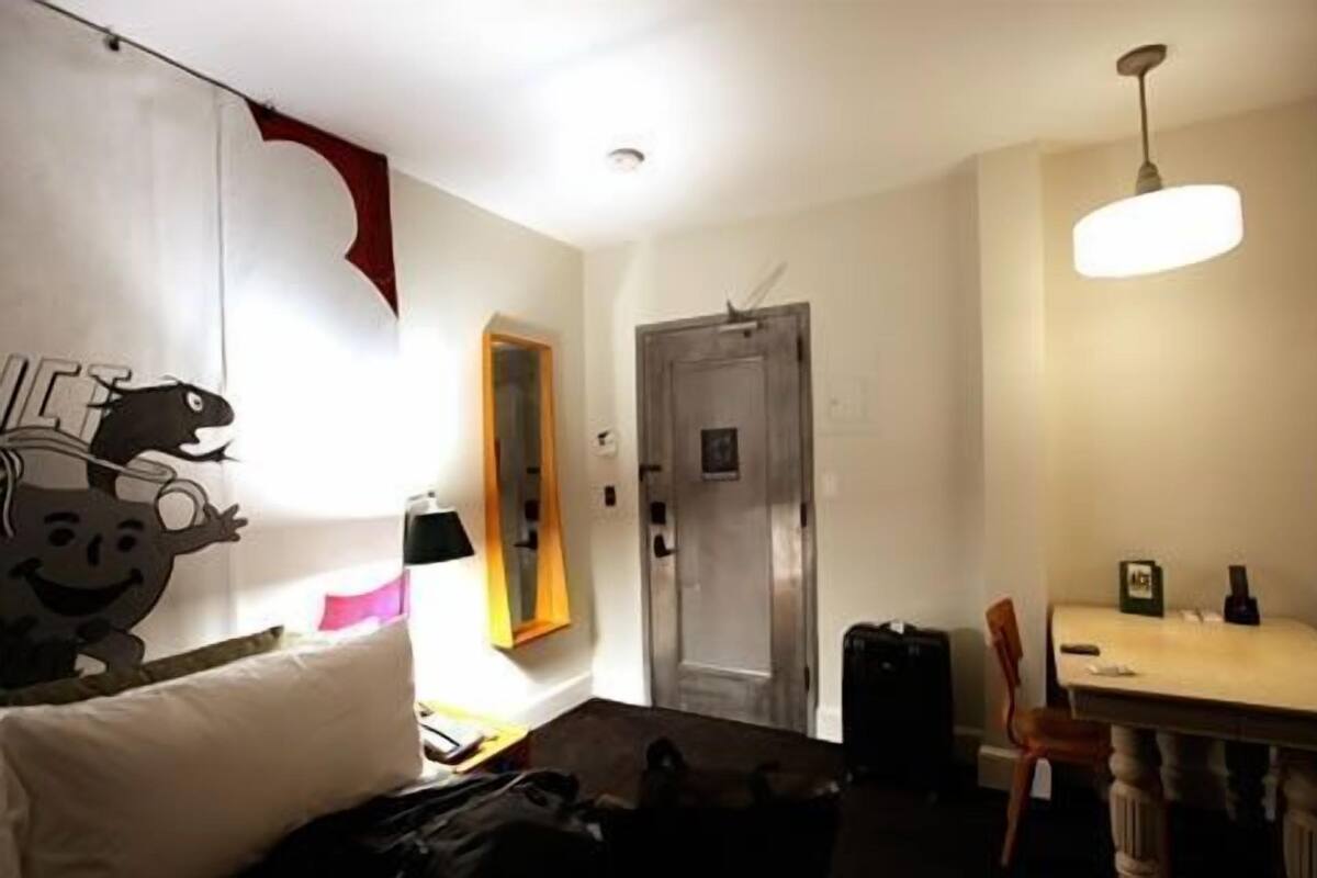 A room with a bed, a desk, a chair, a door, and a wall with a decorative element.