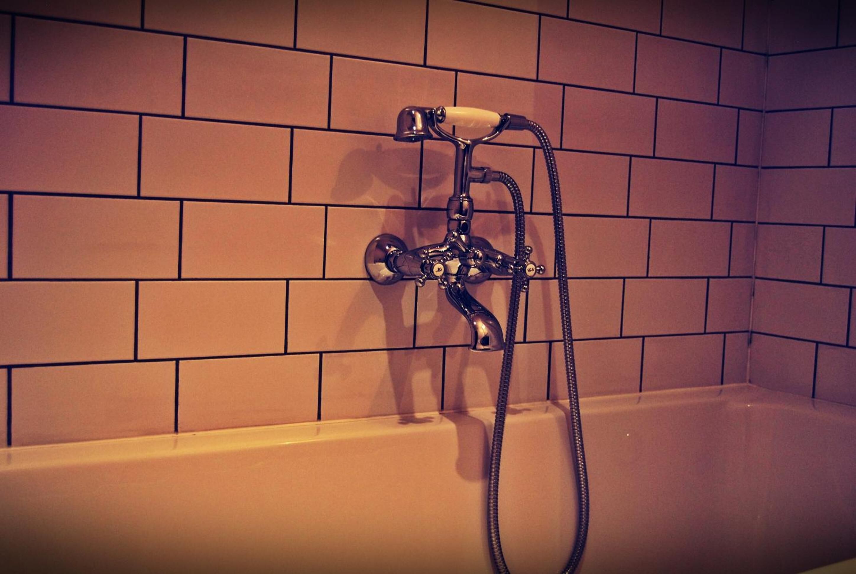 A bathroom with a bathtub, a showerhead, and a faucet.