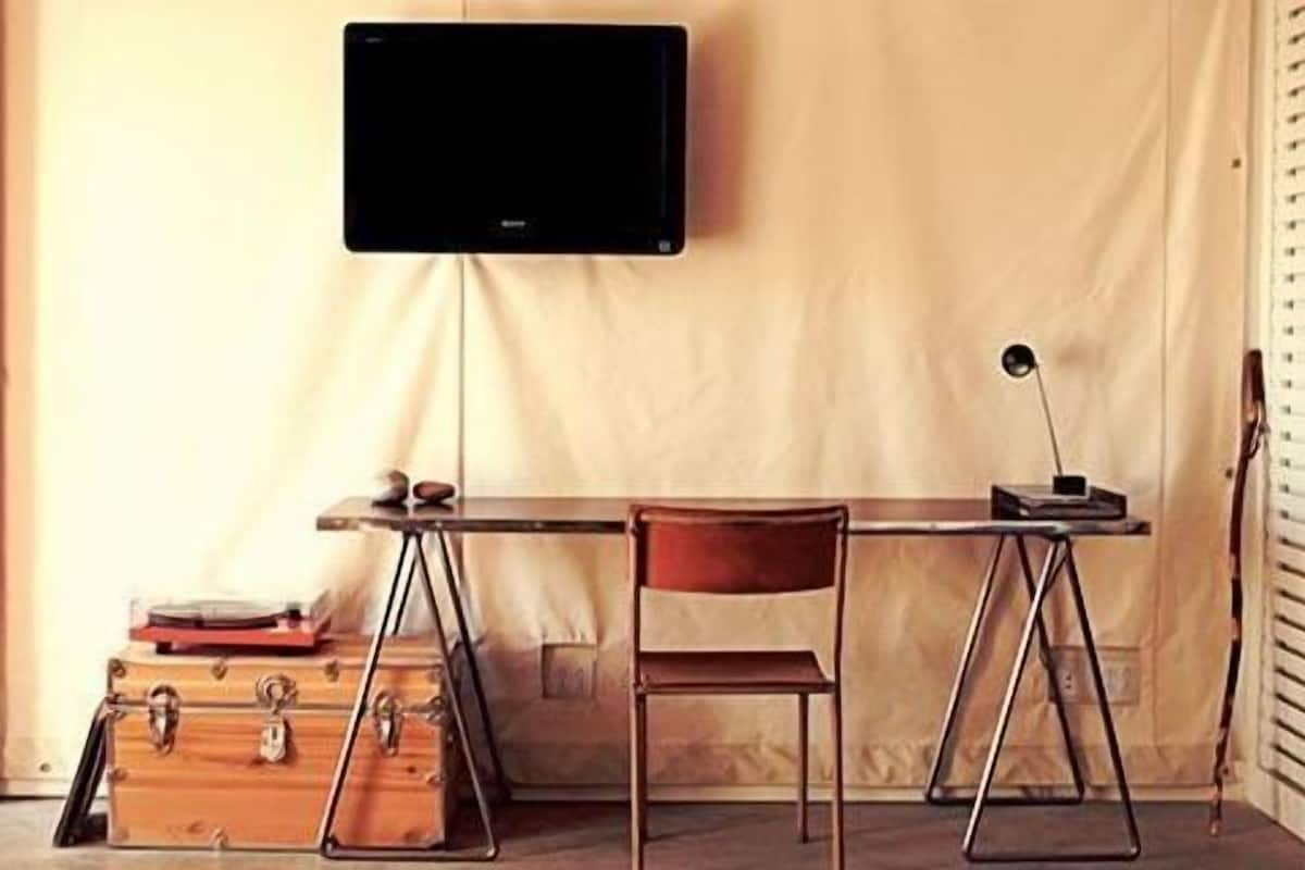 A compact workspace with a desk, chair, and a mounted television.