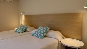 Ein Hotelzimmer mit zwei Betten, einem runden Tisch und einer Wandleuchte.