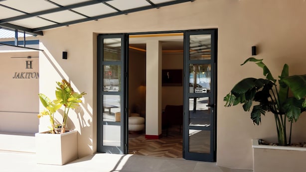Ein moderner Hotel Eingang mit Glastür, einer Treppe und Blumentöpfen.