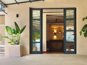 L’entrée d’un hôtel, avec une porte en verre, une plante en pot et un ventilateur de plafond.