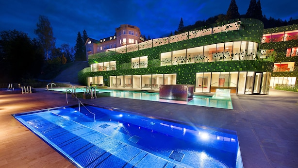 Una piscina techada, una piscina al aire libre, sombrillas